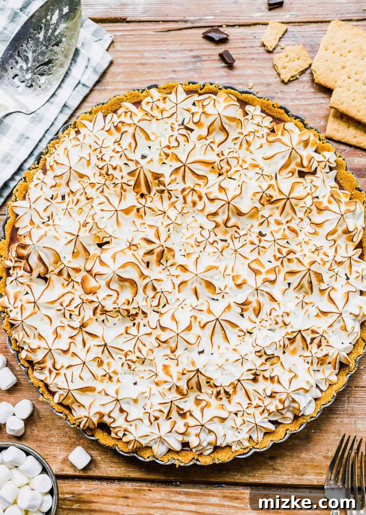 This s'mores tart recipe takes just 15 minutes to make! With a graham cracker crust, ganache filling, and toasty meringue, it's irresistible. Overhead view of the finished s'mores tart with toasted meringue
