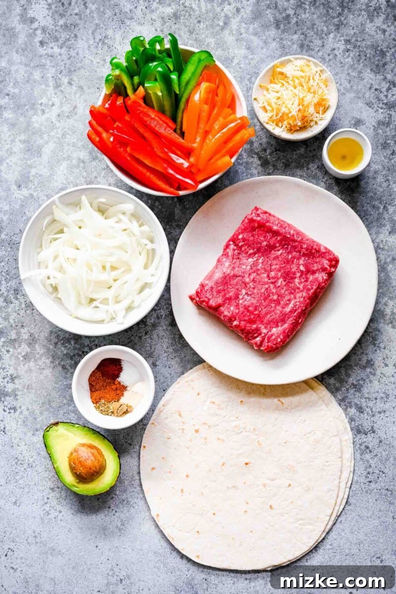 Sizzling Ground Beef Fajitas 4 Ingredients laid out for ground beef fajitas: various colored bell peppers, shredded cheese, oil, ground beef, tortillas, avocado, seasonings, and sliced onions.