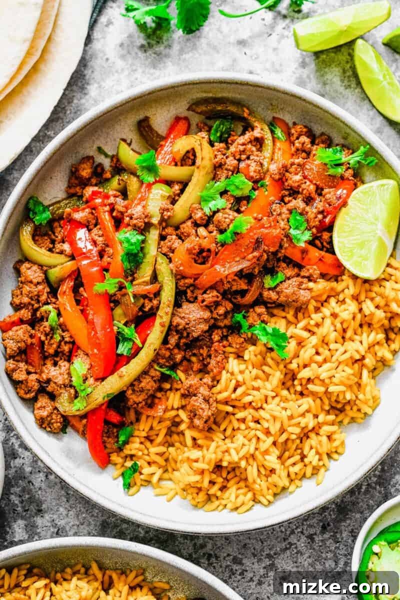 Sizzling Ground Beef Fajitas 10 A white bowl is filled with rice, colorful veggies, and seasoned ground beef, creating a satisfying fajita bowl.