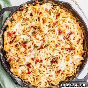 baked chicken spaghetti in a cast iron skillet with fresh parsley on top