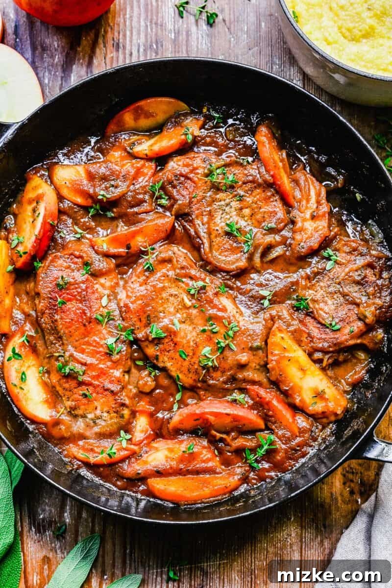 Spiced Apple Butter Pork Chops 3 A large black pan is filled with cooked pork chops in apple butter sauce.