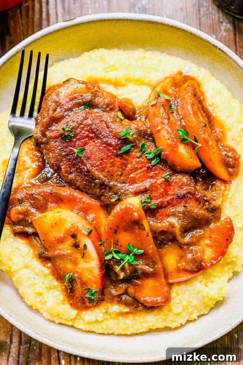 Spiced Apple Butter Pork Chops 4 A fork is placed next to a serving of polenta and apple butter pork chops.