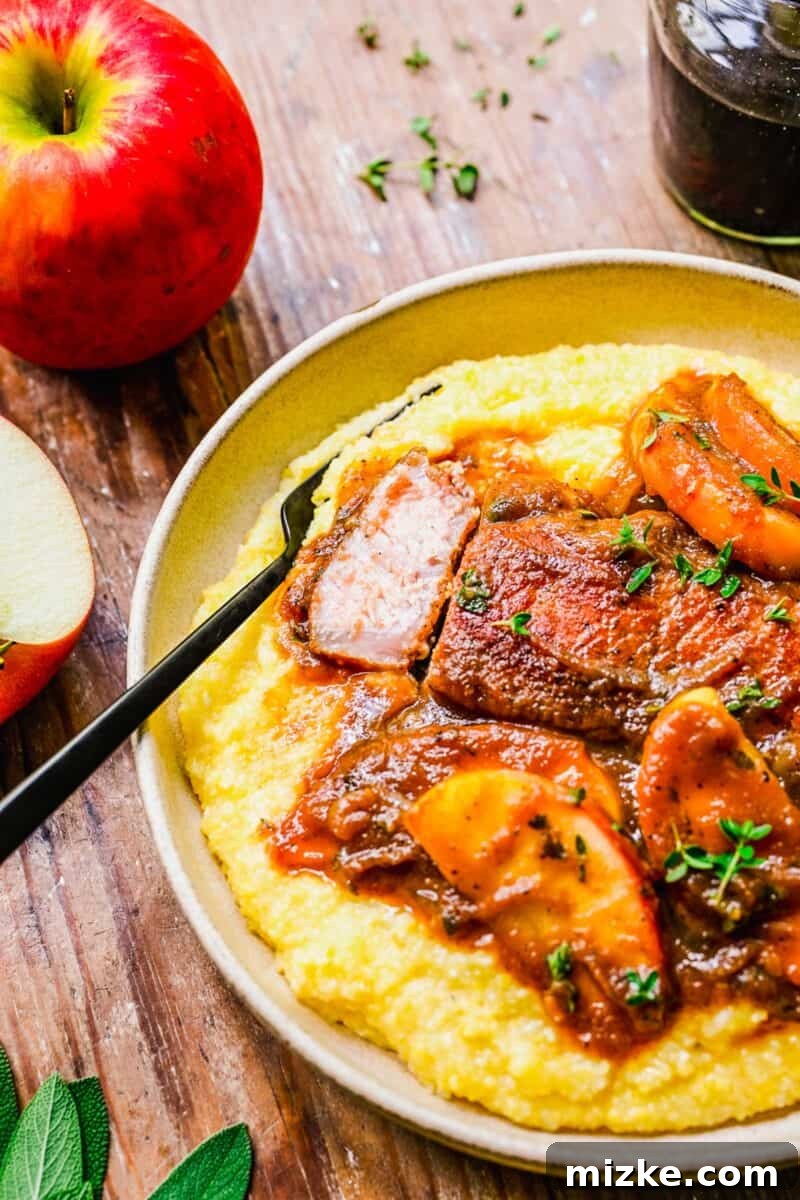 Spiced Apple Butter Pork Chops 6 A piece of cooked pork is placed by a fork on a full plate of food.