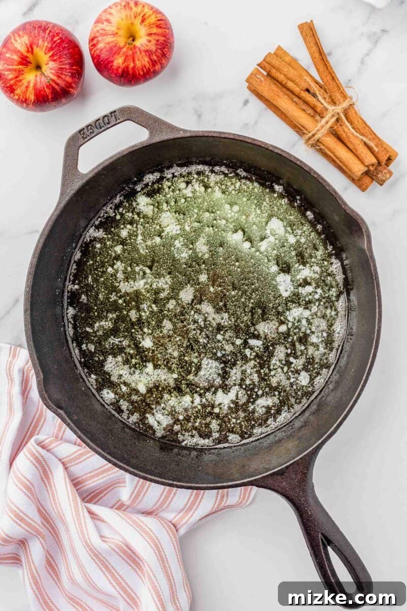 Puffy Apple Cinnamon Dutch Baby 5 Melted butter glistens at the bottom of a hot cast-iron skillet, ready for the pancake batter.