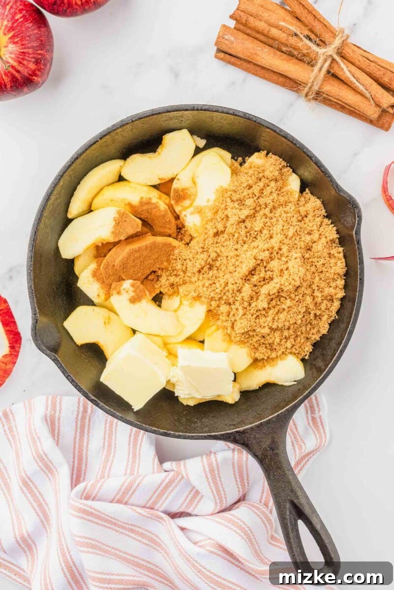 Puffy Apple Cinnamon Dutch Baby 7 Thinly sliced apples, brown sugar, a pat of butter, and ground cinnamon are neatly arranged in a medium skillet, ready to be cooked into a compote.