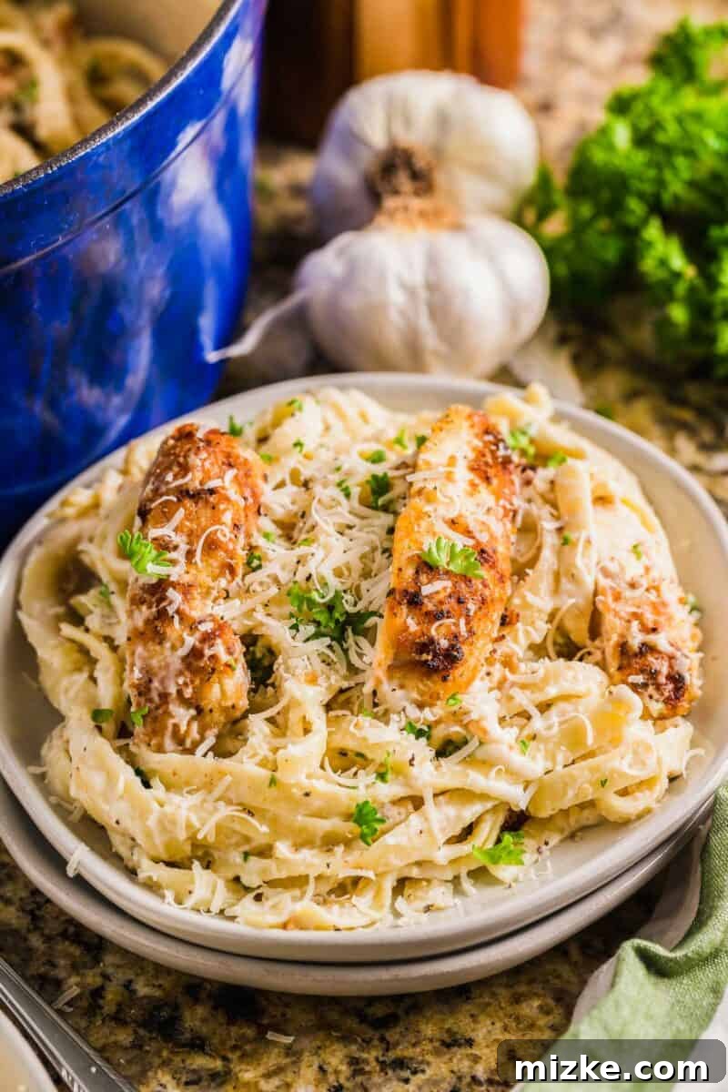 Creamy Garlic Parmesan Chicken Pasta 11 Parsley and parmesan garnish a plate filled with pasta and chicken.