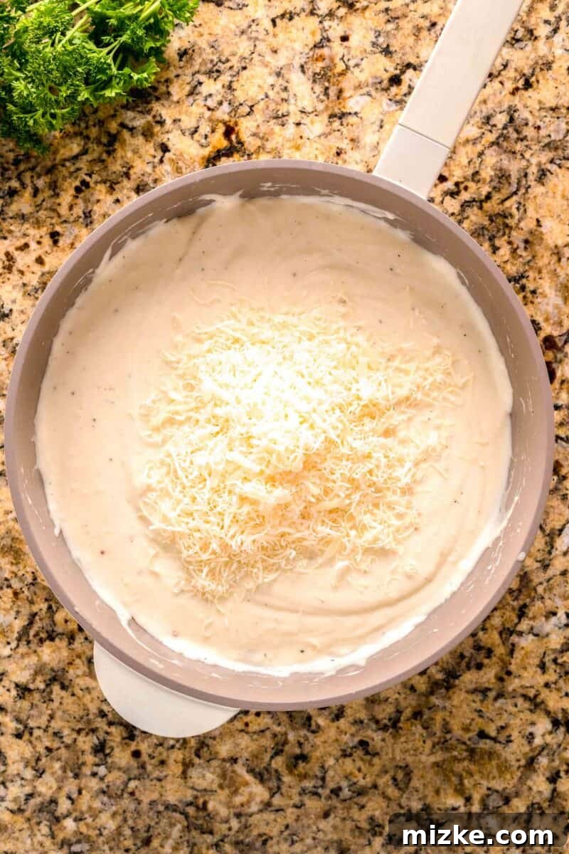 Creamy Garlic Parmesan Chicken Pasta 8 garlic parmesan cream sauce mixture with parmesan cheese on top in a nonstick skillet