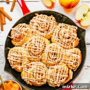 Apple pie cinnamon rolls baked in a cast iron skillet.