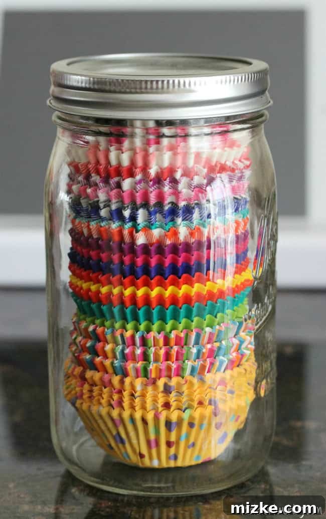 Organize Your Cupcake Liners Like a Pro 3 A close-up view of various colorful cupcake liner designs neatly arranged within a clear glass mason jar, ready for use.