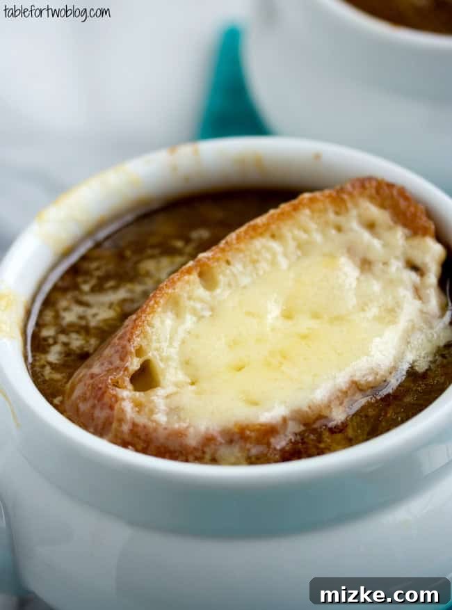Close-up of a rustic bowl of French Onion Soup, showing the rich, caramelized onion broth beneath the toasted bread and melted cheese.