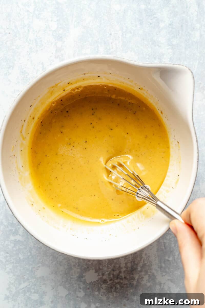 Carefully whisking the savory-sweet maple-Dijon sauce for the chicken. Whisking together Dijon mustard, maple syrup, rice wine vinegar, salt, and pepper for the sauce.