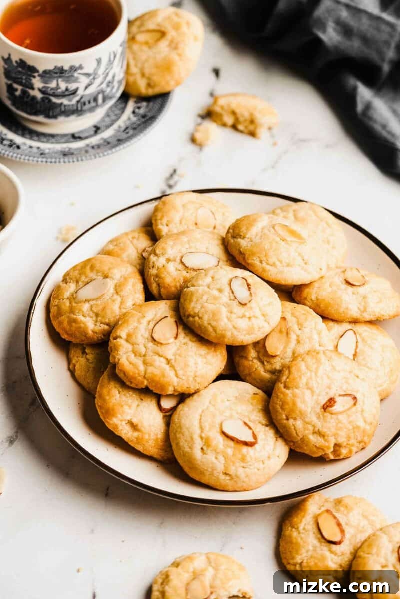 Stacked Chinese almond cookies on a decorative plate, ready for serving, highlighting their golden-brown color and almond topping.