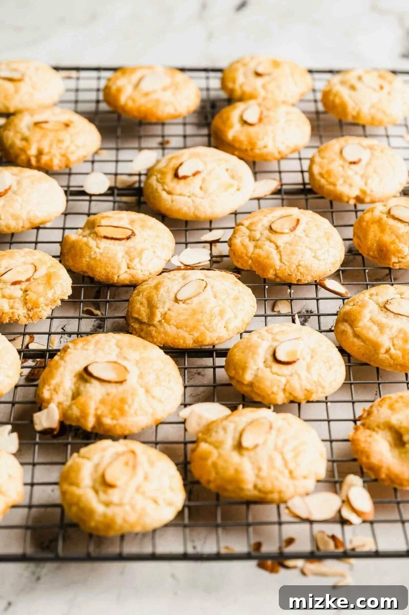 Arrangement of baked Chinese almond cookies with almond garnishes on a wire cooling rack.