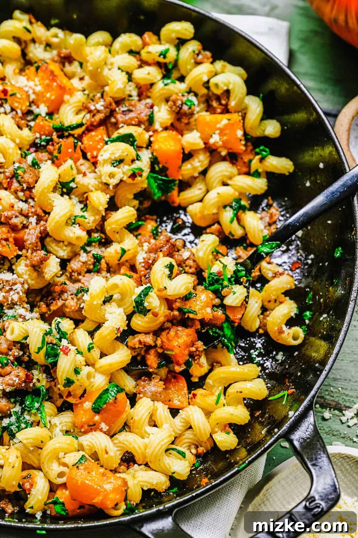 Creamy Pumpkin Sausage Pasta 4 Up close shot of cooked pasta mixed with pumpkin and sausage inside the pot, a spoon ready for serving.