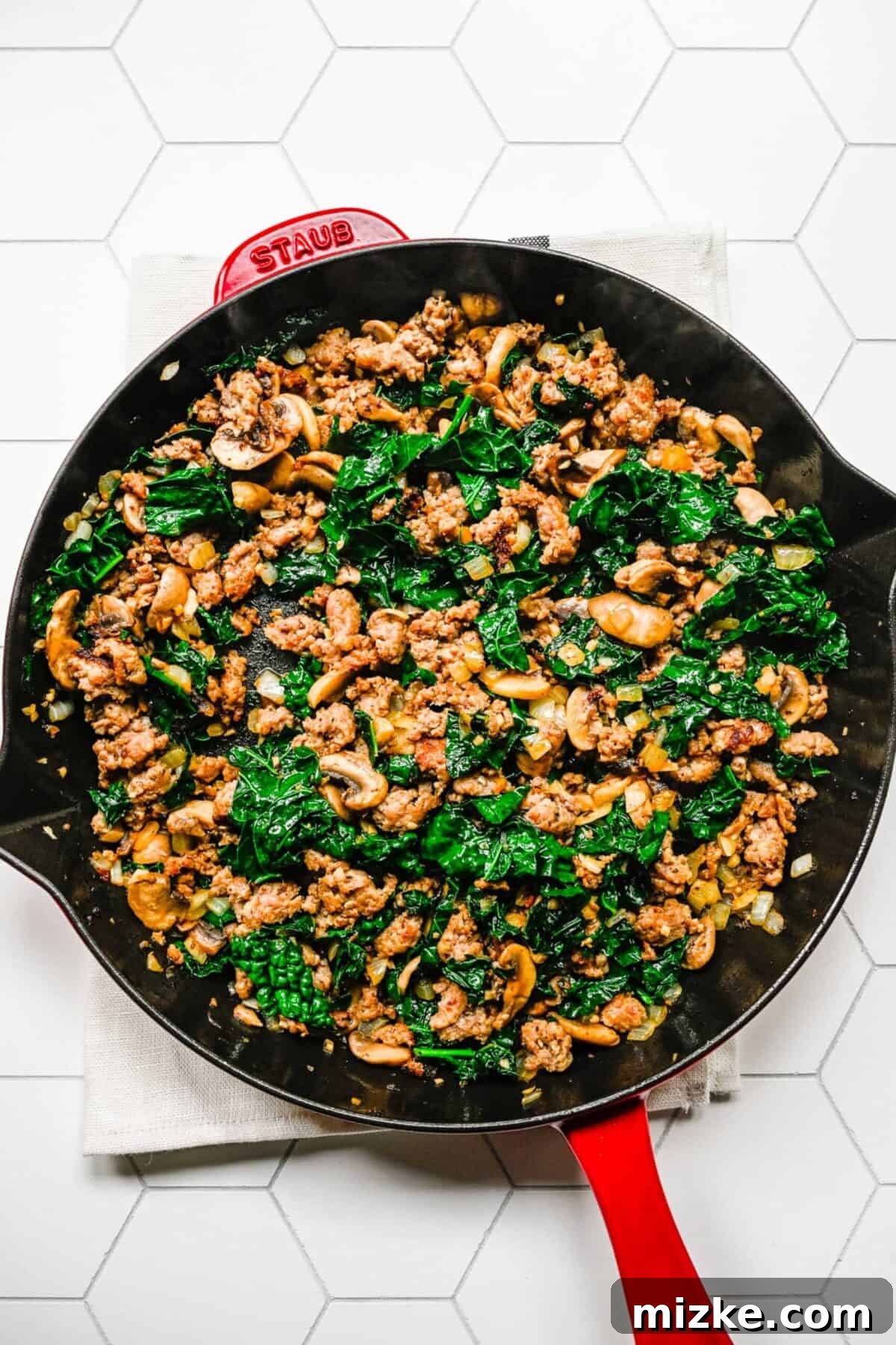 Flavorful sausage and kale mixture, ready for layering A skillet filled with cooked Italian sausage, kale, mushrooms, onion, and garlic, perfectly sautéed