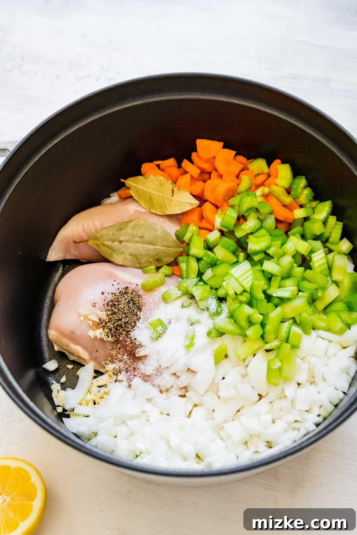 Zesty Lemon Chicken Rice Soup 5 Raw chicken, bay leaves, uncooked carrots, celery, onion, and seasonings neatly arranged in a large pot, ready for simmering