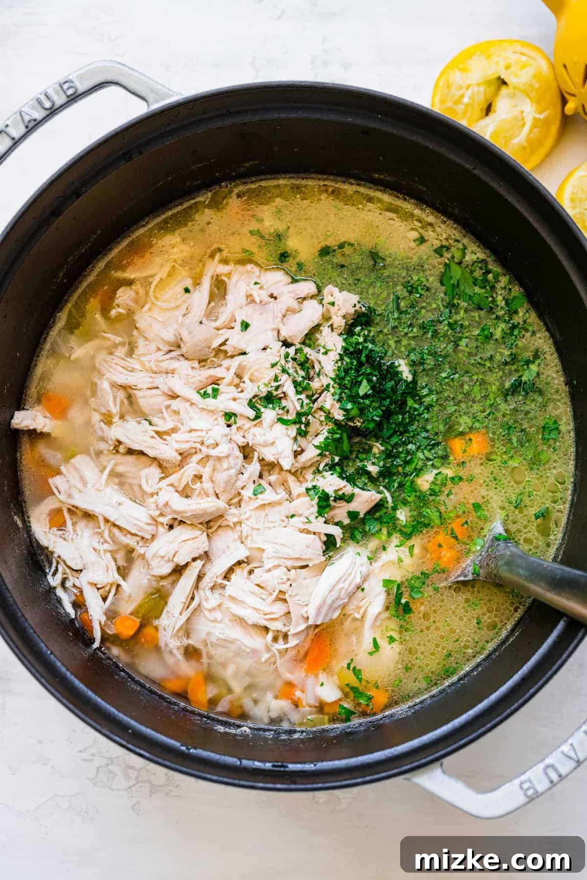 Zesty Lemon Chicken Rice Soup 8 Shredded chicken being added back into a large pot of simmering soup with vegetables