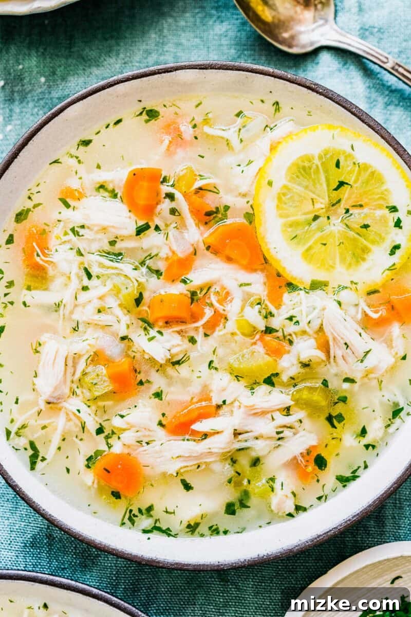 Zesty Lemon Chicken Rice Soup 10 Up-close, overhead shot of a steaming bowl of vibrant lemon chicken and rice soup, garnished with fresh herbs and a lemon slice
