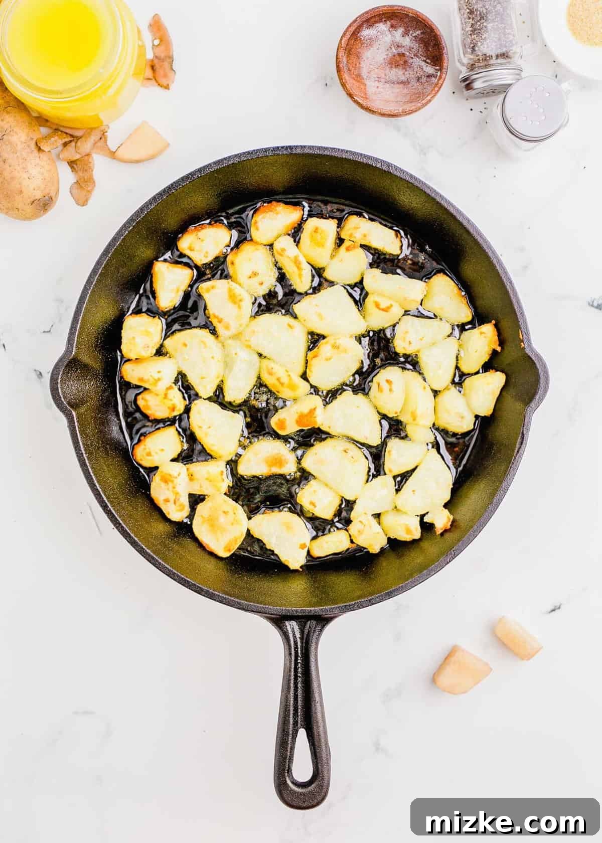 Shatteringly Crisp Duck Fat Potatoes 8 Overhead shot of parboiled and roughed-up potatoes being carefully placed into hot duck fat in a cast iron skillet for initial frying