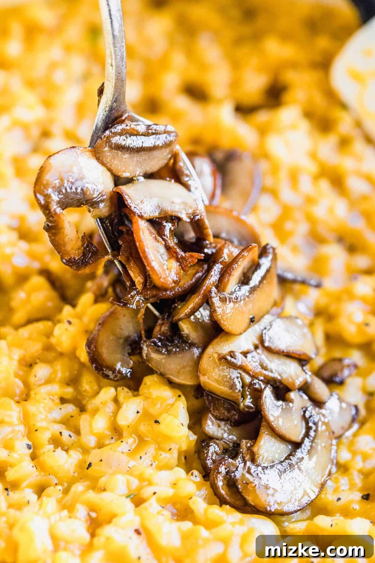Enjoying the rich flavors of vegan mushroom risotto with perfectly cooked mushrooms. A close-up shot of tender, roasted mushrooms elegantly balanced on a fork, positioned just above a serving of creamy vegan mushroom risotto.