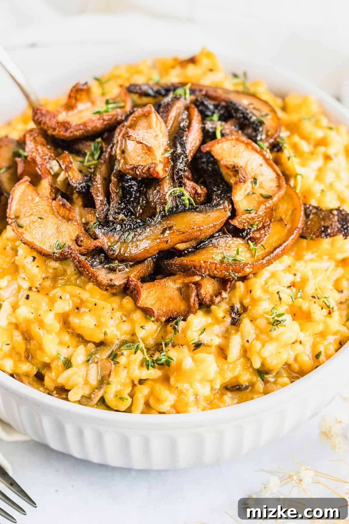 Delicious vegan mushroom risotto in a casserole dish, ready to be enjoyed. A close-up shot of a rustic casserole dish filled with creamy vegan mushroom risotto, beautifully garnished with an abundance of sautéed mushrooms on top.