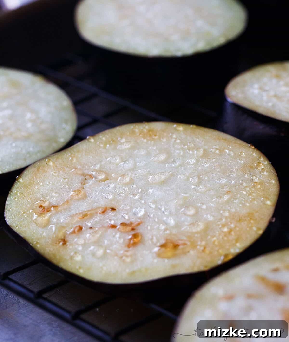 Rustic Eggplant Parmesan Delight 2 Close-up shot of salted eggplant slices with beads of moisture forming on their surface, demonstrating the salting process.