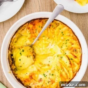 overhead image of a wooden cutting board and potatoes au gratin in a white casserole dish with a silver spoon that has scooped out some of the side dish.