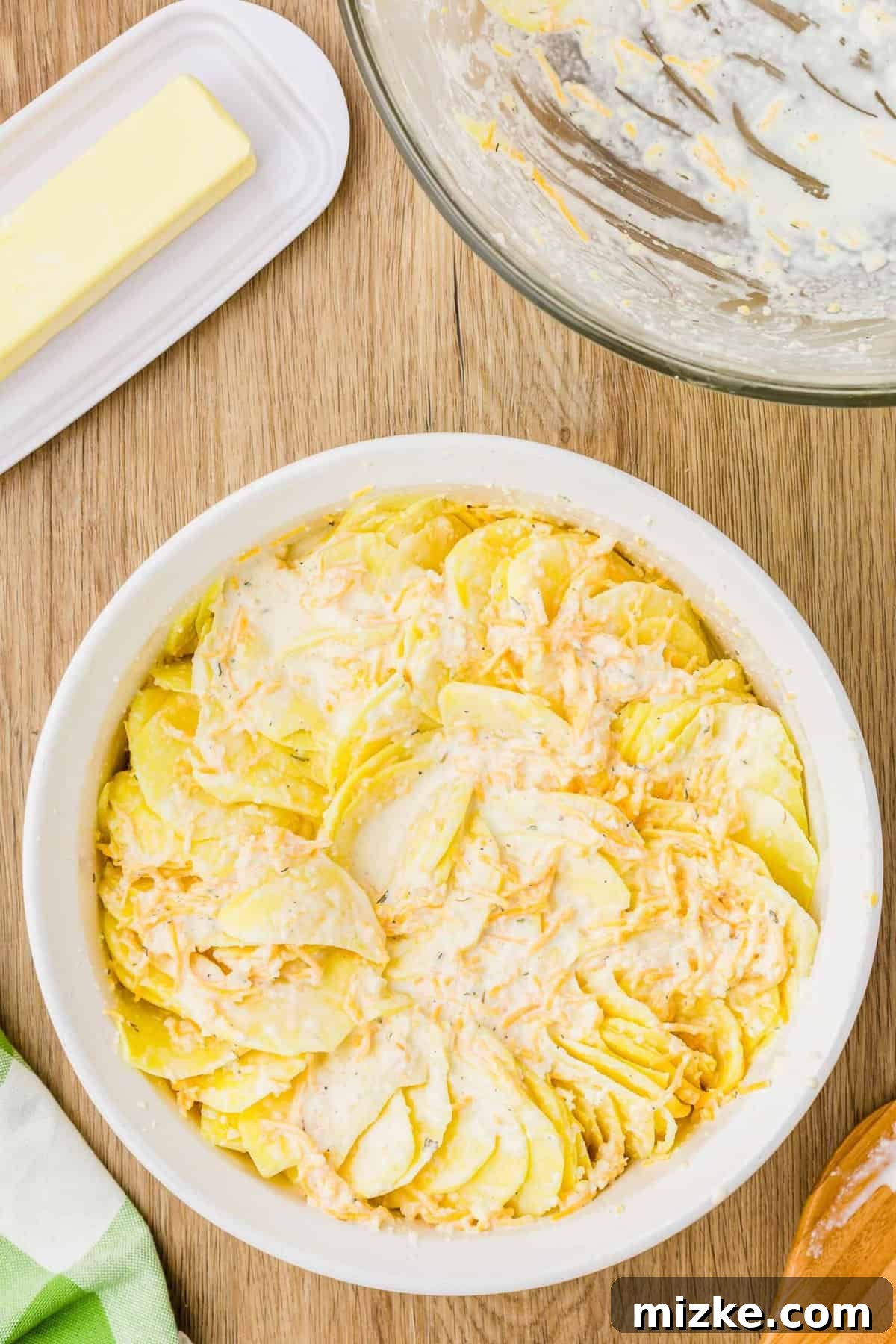 Simply Irresistible Creamy Potato Gratin 9 Layers of thinly sliced potatoes meticulously arranged in a baking dish, with the rich cream and cheese mixture poured over the top, poised for baking.