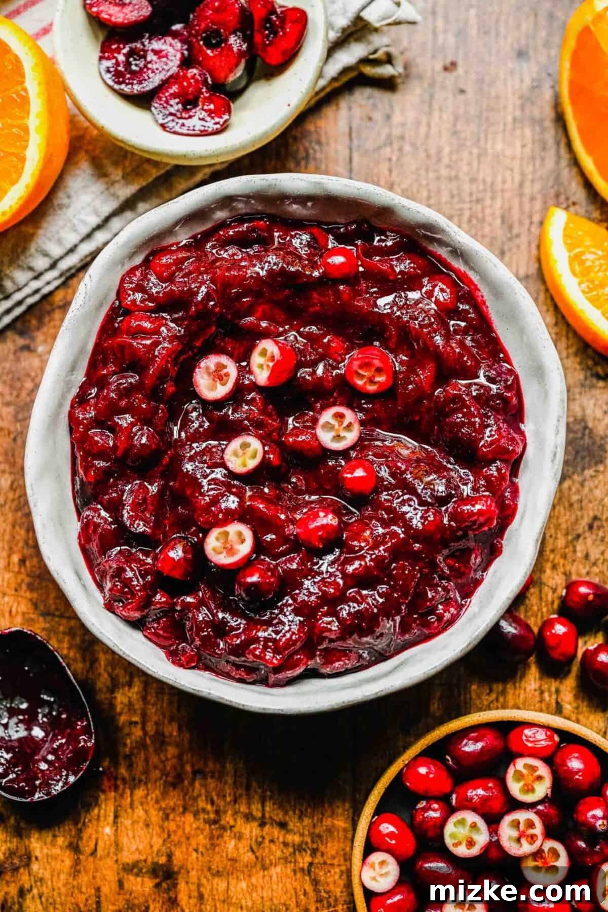 This cranberry cherry compote recipe is tart and sweet, takes only 25 minutes to make, and can be made in advance for any Thanksgiving meal. A bowl of cranberry cherry compote, topped with fresh cranberries, next to a bowl of cranberries and a bowl of cherries