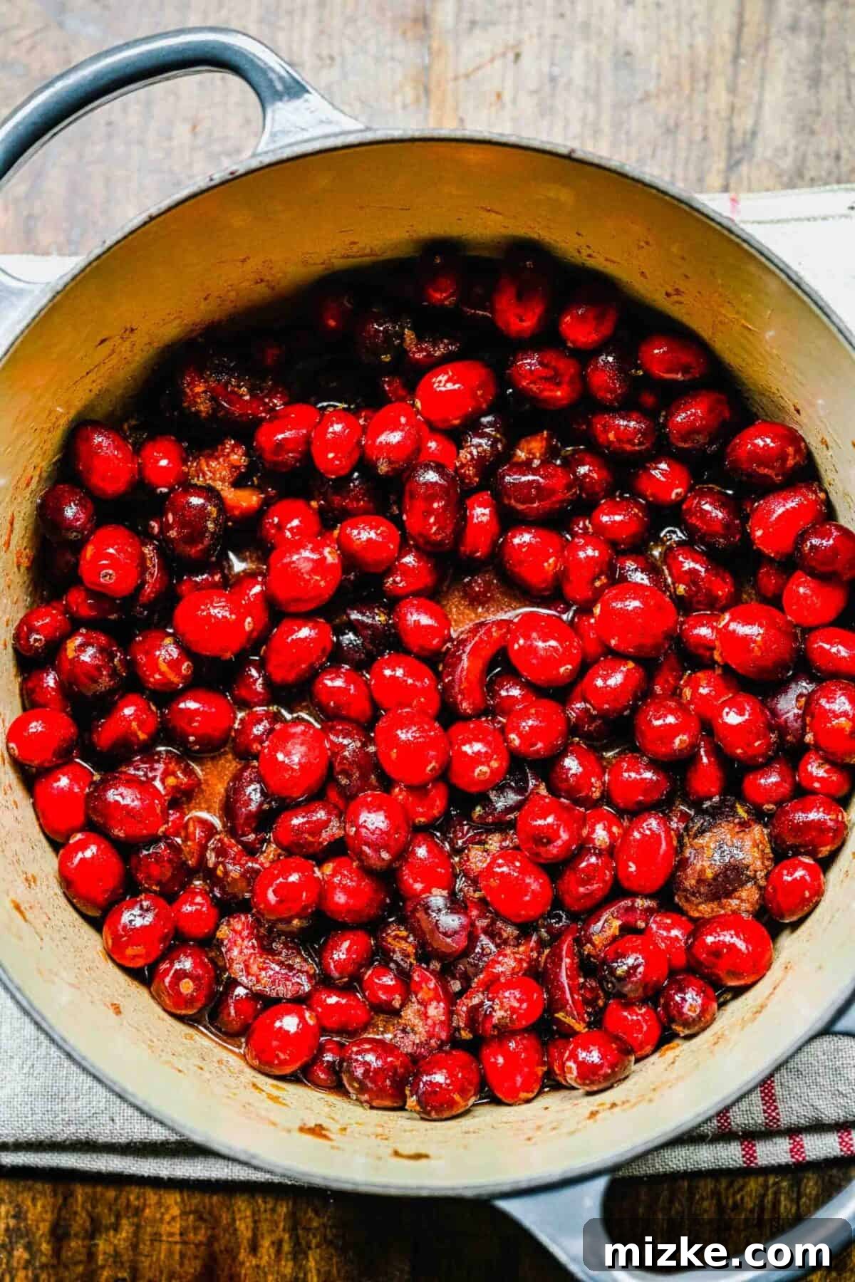This cranberry cherry compote recipe is tart and sweet, takes only 25 minutes to make, and can be made in advance for any Thanksgiving meal. Cranberries and cherries cooking in a pot with brown sugar, orange juice, and orange zest