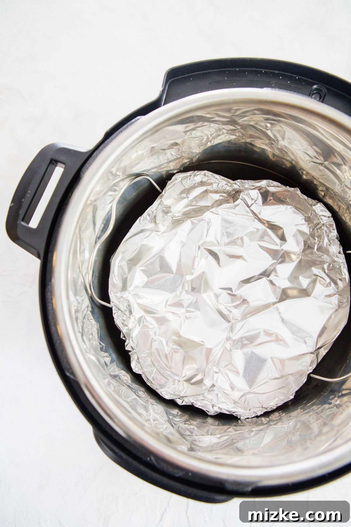 Fluffy Instant Pot Egg Bites 11 Egg molds covered in aluminum foil on a metal rack in the insert of an Instant Pot, demonstrating the setup for pressure cooking.