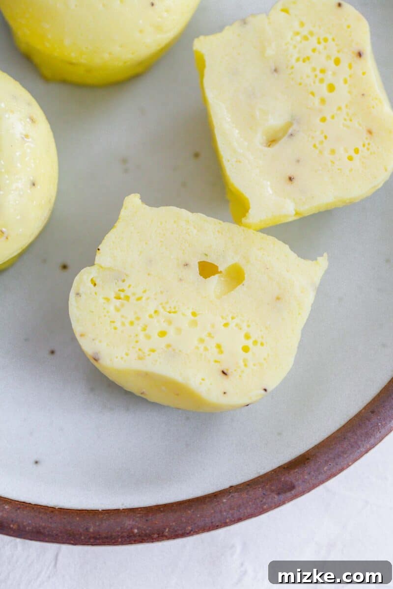 Fluffy Instant Pot Egg Bites 5 An Instant Pot egg bite sliced in half on a ceramic plate with a brown rim, showing its light and fluffy interior texture.