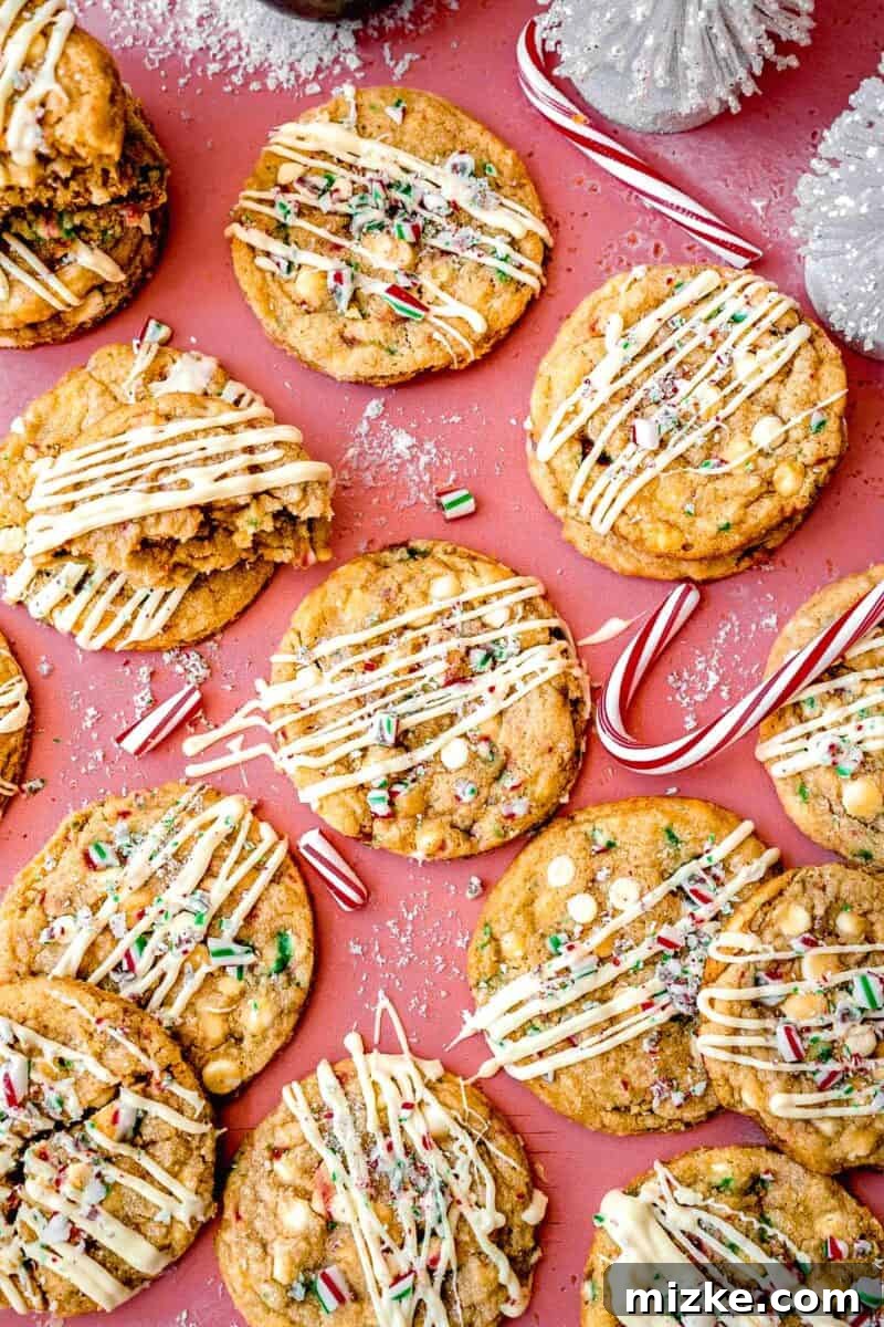 White Chocolate Peppermint Bliss Cookies 2 overhead image of peppermint white chocolate cookies with white chocolate drizzle on a dark pink background with candy canes scattered around