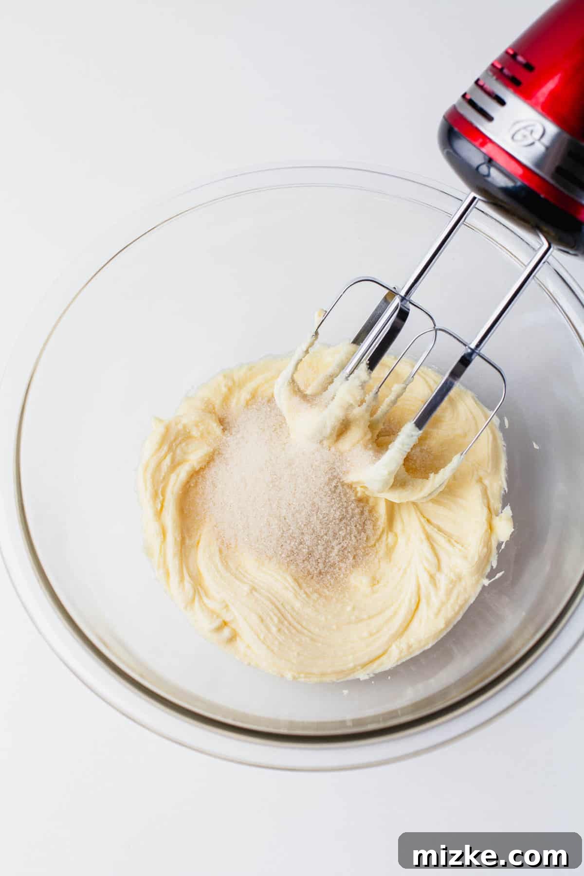 Melt-in-Your-Mouth Snowballs 5 butter and sugar in a large clear bowl being creamed together with a red hand mixer