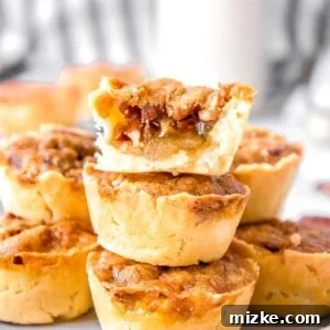 Effortless Pecan Tassie Bites 13 A perfectly baked pecan tassie, bitten in half, revealing its sweet, gooey filling and tender crust.