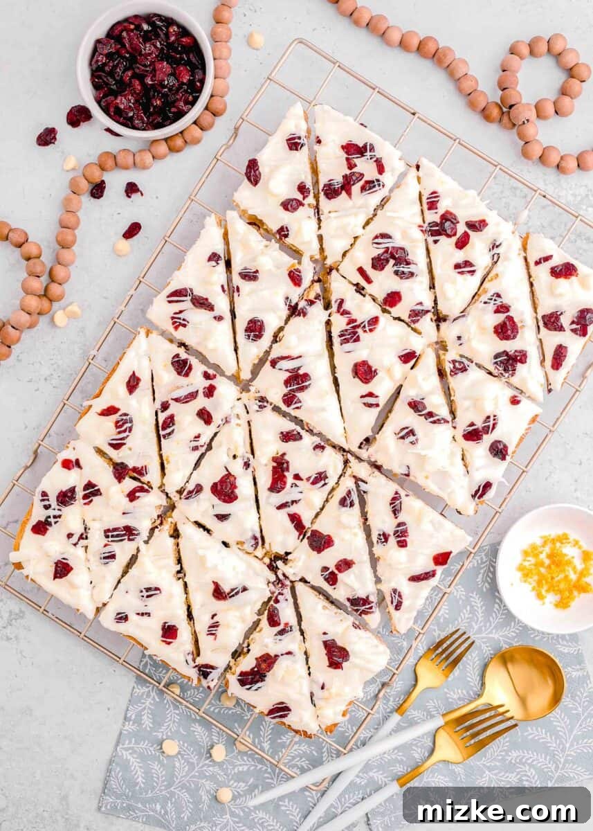 Bake Your Own Cranberry Bliss 18 An entire sheet of cranberry bliss bars, beautifully cut into triangles, resting on a metal baking rack, with a decorative bead necklace draped around the tray.