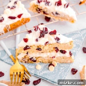 Cranberry bliss bars arranged on a blue floral napkin, with a metal baking rack holding more bars in the background.