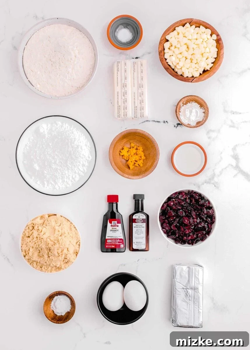 Bake Your Own Cranberry Bliss 4 A flat lay of all ingredients for cranberry bliss bars: flour, salt, butter, white chocolate chips, baking powder, salt, dried cranberries, cream cheese, eggs, cornstarch, brown sugar, powdered sugar, orange zest, orange extract, and vanilla extract.
