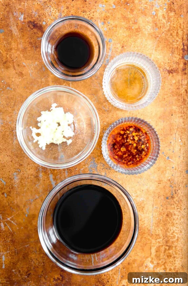 Your New Favorite Dumpling Sauce 4 A vibrant overhead shot showcasing the five essential ingredients for an authentic dumpling sauce, neatly arranged: a bowl of dark, aged black vinegar, a small dish of golden, aromatic sesame oil, a spoonful of fiery and textural chili crisp, a bottle of rich sweet soy sauce, and a pile of freshly minced pungent garlic.