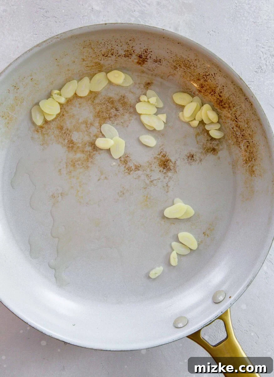 Thinly sliced garlic sautéing in a hot skillet with a small amount of oil until fragrant and lightly golden.