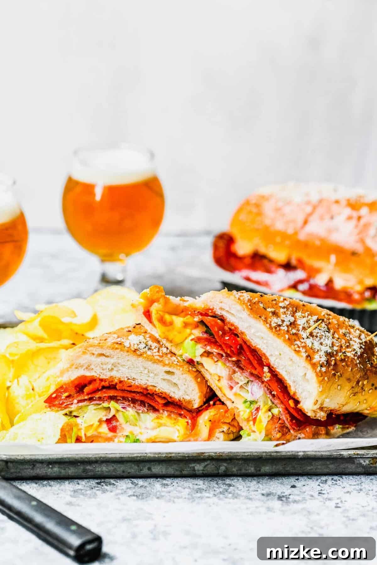 The ultimate grinder sandwich, bursting with layers of flavor, served fresh. A perfectly sliced grinder sandwich revealing its layers of meat, cheese, and fresh salad, served with two glasses of beer.
