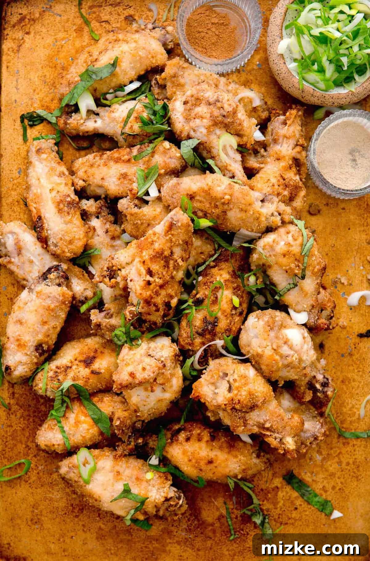 Overhead shot of perfectly baked and browned Chinese salt and pepper chicken wings, generously garnished with fresh herbs.