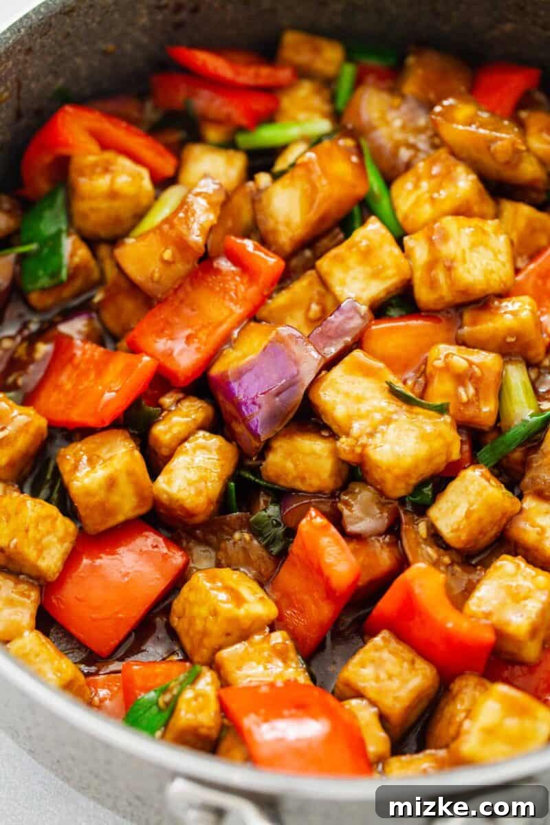 Detailed up-close image of the glossy brown sauce coating the crispy tofu and tender eggplant pieces in a skillet, showcasing the rich texture of the dish.