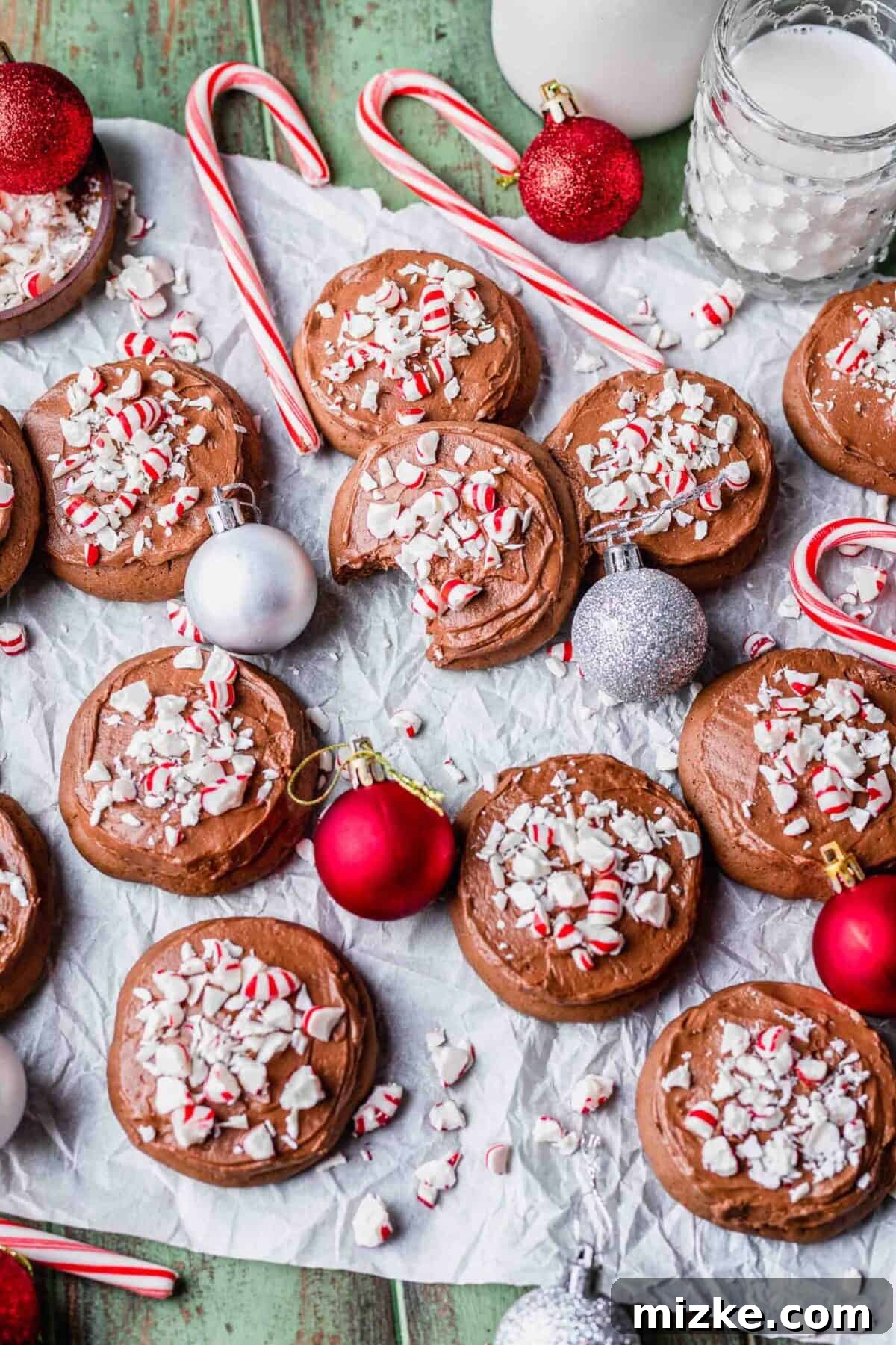 These chocolate peppermint lofthouse cookies are moist, decadent, and bursting with flavor, making them the perfect Christmas cookie. Overhead view of many chocolate peppermint lofthouse cookies, topped with candy canes and surrounded by Christmas ornaments