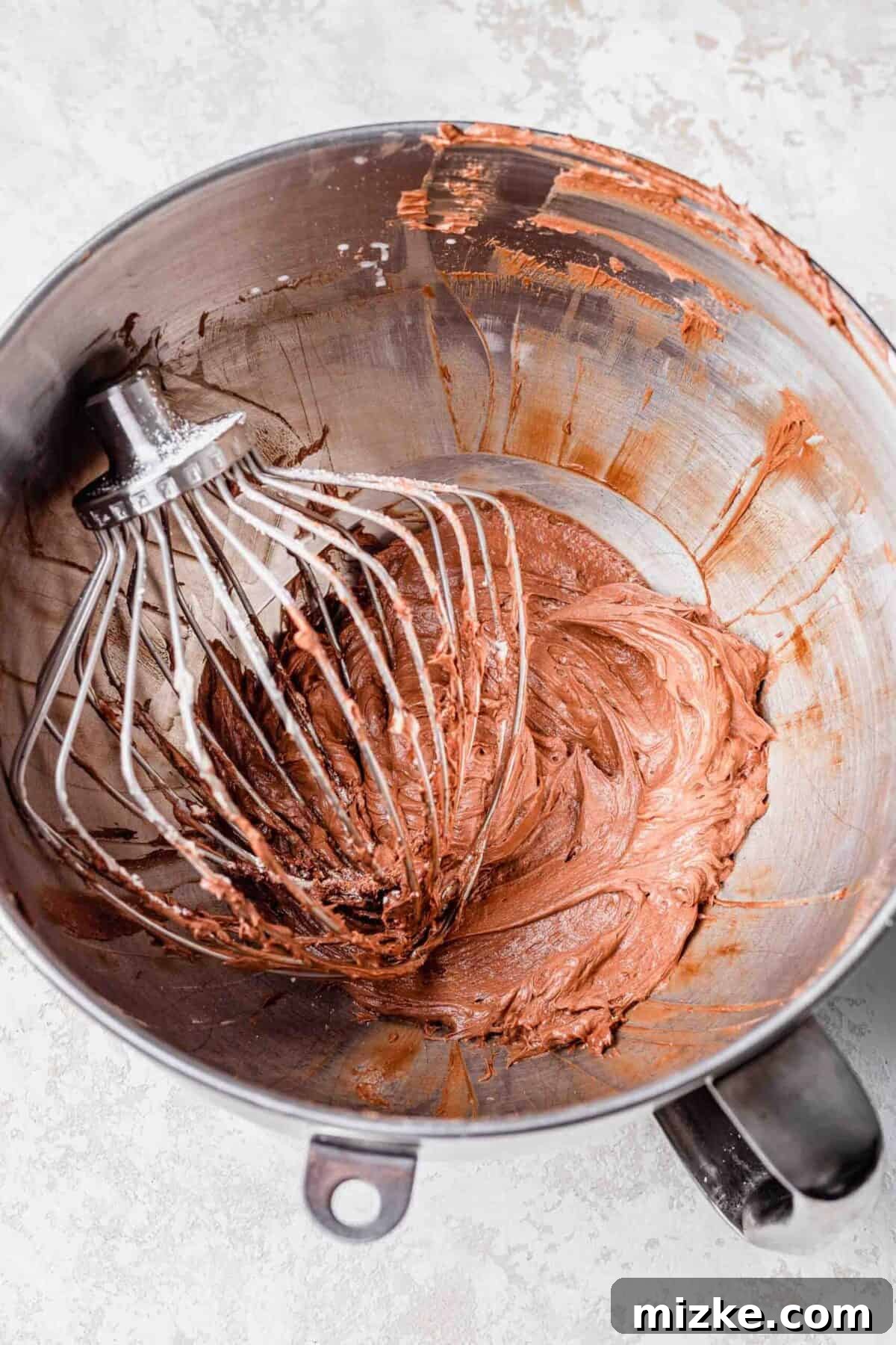 These chocolate peppermint lofthouse cookies are moist, decadent, and bursting with flavor, making them the perfect Christmas cookie. A stand mixer bowl filled with chocolate peppermint frosting, with a whisk attachment in it