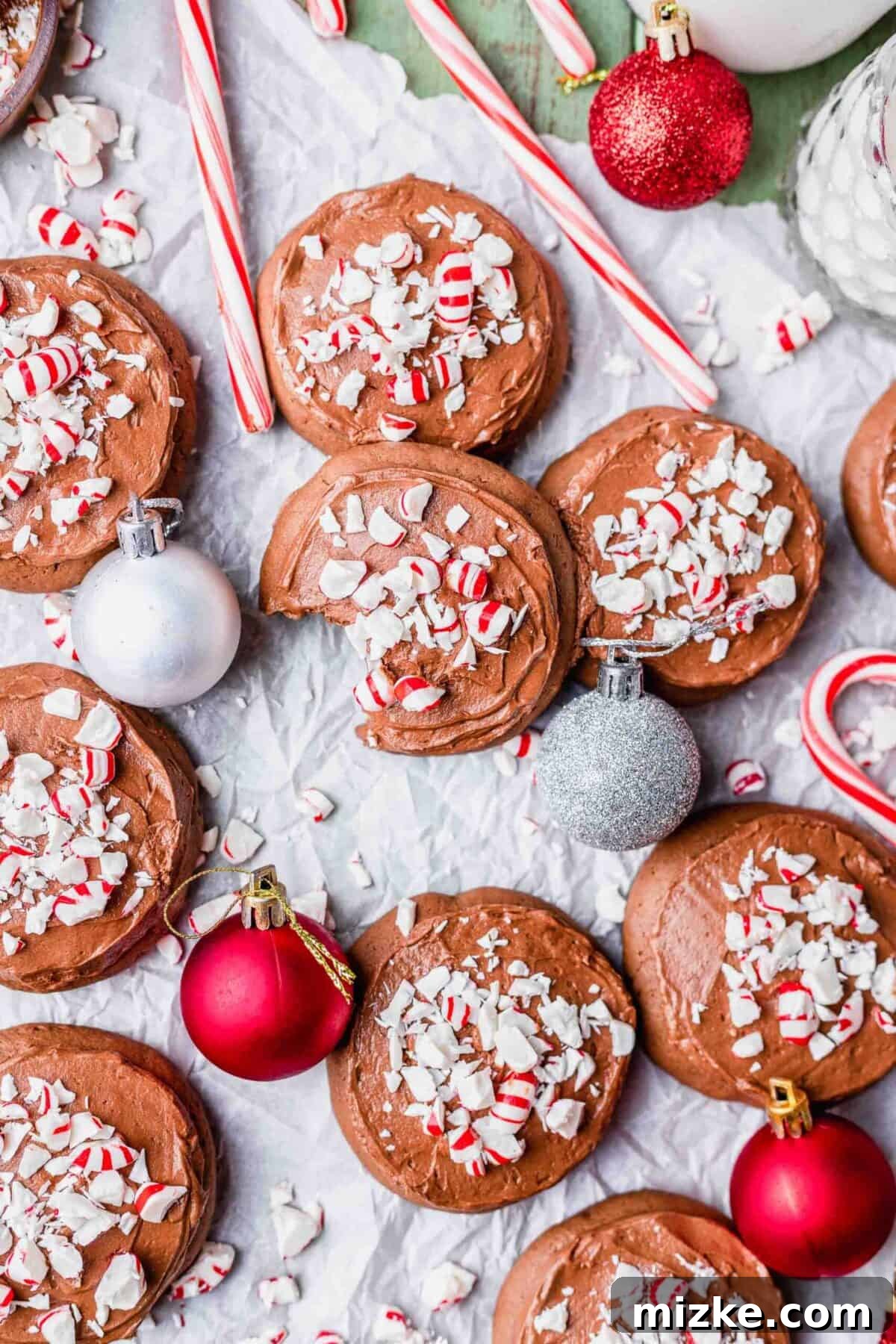 These chocolate peppermint lofthouse cookies are moist, decadent, and bursting with flavor, making them the perfect Christmas cookie. Chocolate peppermint lofthouse cookies, topped with crush candy canes, on a table next to Christmas ornaments