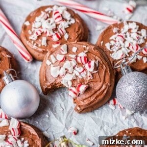 A chocolate peppermint lofthouse cookie with a bite taken out of it, next to other cookies, candy canes, and Christmas ornaments