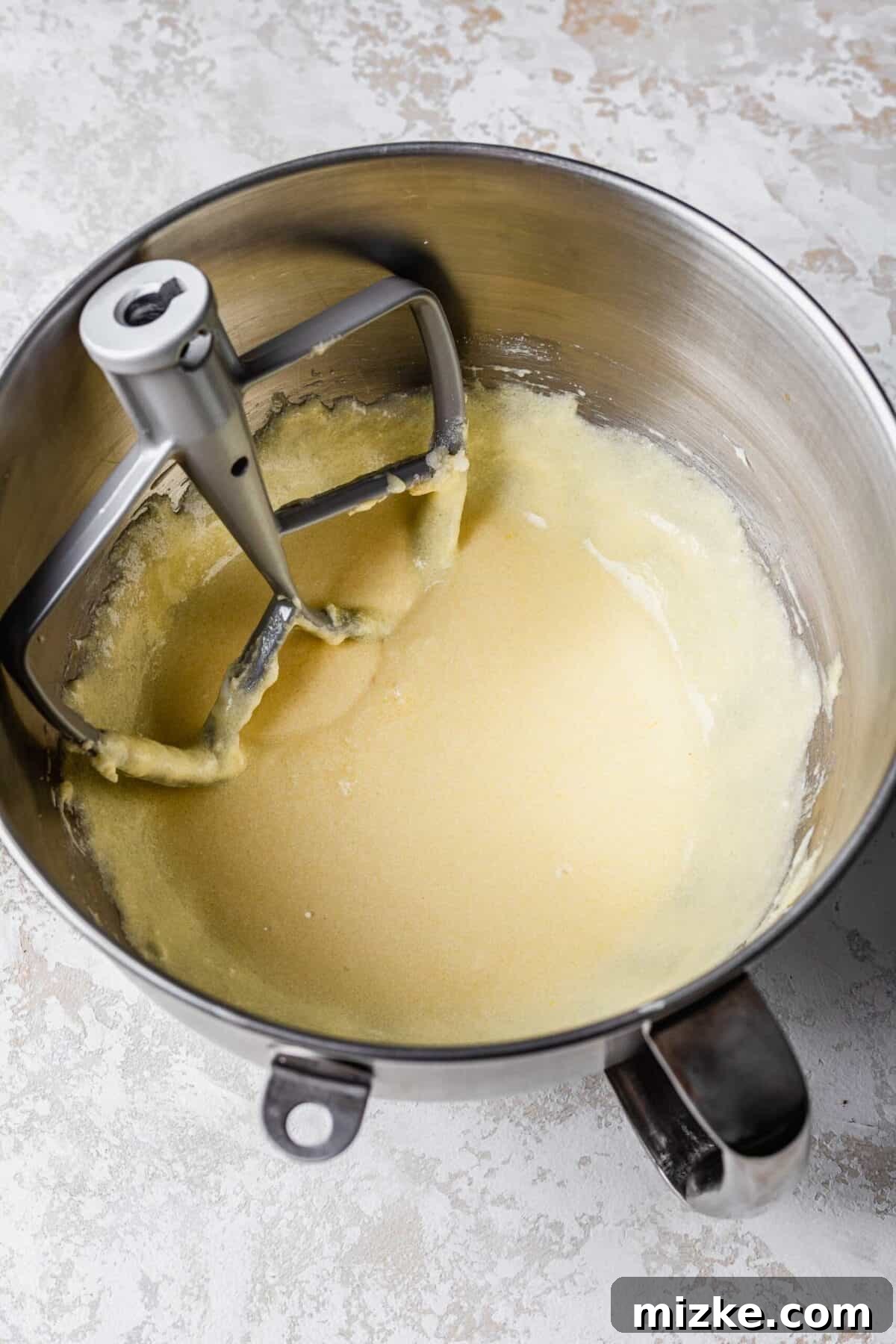These chocolate peppermint lofthouse cookies are moist, decadent, and bursting with flavor, making them the perfect Christmas cookie. A stand mixer bowl filled with beaten butter, sugar, eggs, and sour cream, with the paddle attachment in it