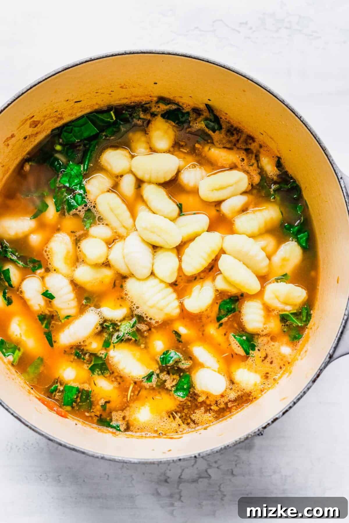 This sausage gnocchi soup recipe is comforting, spicy, and hearty, with kale, tomatoes, and lots of Italian spices. It's perfect for winter! Pillowy gnocchi and vibrant kale added to the simmering sausage and tomato soup, creating a visually appealing and wholesome dish.