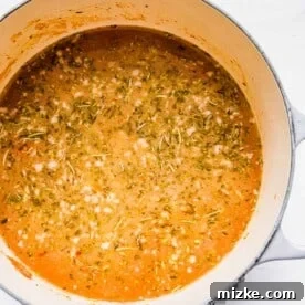 A pout filled with broth and seasonings, as well as onions and sausage